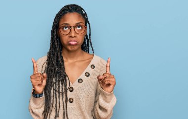 Afrika kökenli Amerikalı kadın, günlük giysiler içinde üzgün ve üzgün görünüyor, parmaklarıyla yön gösteriyor, mutsuz ve depresif.. 