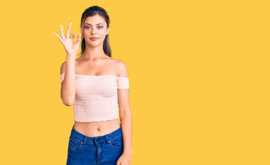 Gündelik kıyafetler giyen, gülümseyen genç ve güzel bir kadın el ve parmaklarıyla 