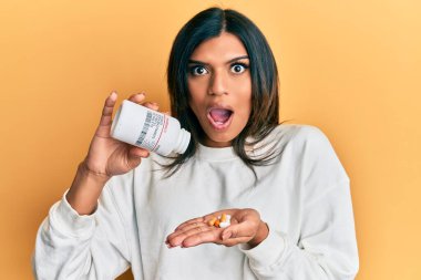 Genç Latin transseksüel kadın elinde haplar tutuyordu şaşkınlık ve şaşkınlık dolu bir ifade, korku ve heyecan dolu bir yüz.. 