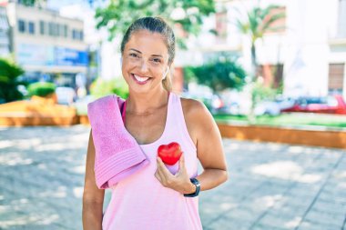 Orta yaşlı sporcu kadın parkta kalbi tutan sağlık sigortası istiyor.