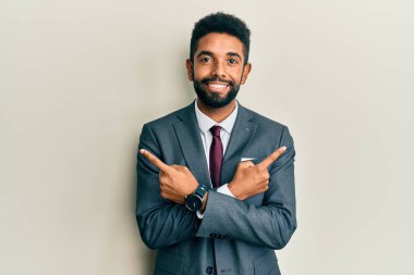 Sakallı, takım elbiseli ve kravatlı yakışıklı bir adam iki tarafı da parmaklarıyla işaret ediyor. 