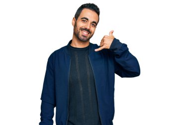 Günlük kıyafetler giymiş, gülümseyen genç İspanyol adam telefonla el ve parmak hareketleri yapıyor telefonda konuşur gibi. iletişim kavramları. 