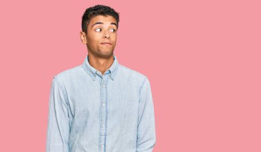 Genç, yakışıklı, Afro-Amerikalı, günlük kıyafetler giyen, gülümseyen, yan bakan ve düşünen.. 