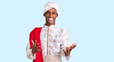 Gelenek giyinmiş Afrikalı yakışıklı bir adam Sherwani sari elbiseleri giyiyor. Neşeli gülümsüyor ve kollarını açıyor. Hoş geldin, olumlu ve kendinden emin selamlar. 