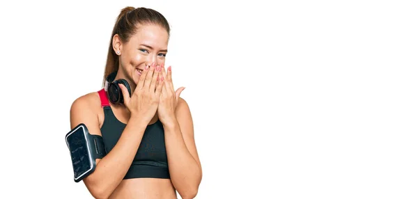 Beautiful Blonde Woman Wearing Gym Clothes Using Headphones Laughing Embarrassed — Stock Photo, Image