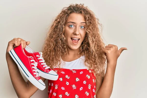 Menina Adolescente Branca Bonita Segurando Sapatos Casuais Vermelhos Apontando Polegar — Fotografia de Stock