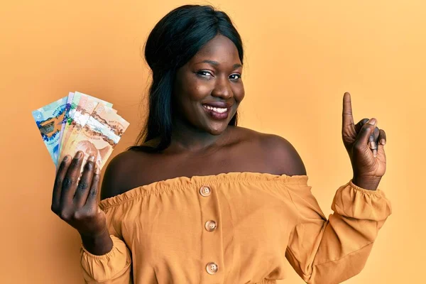 Afričanky Mladá Žena Drží Kanadské Dolary Úsměvem Šťastný Ukazuje Rukou — Stock fotografie
