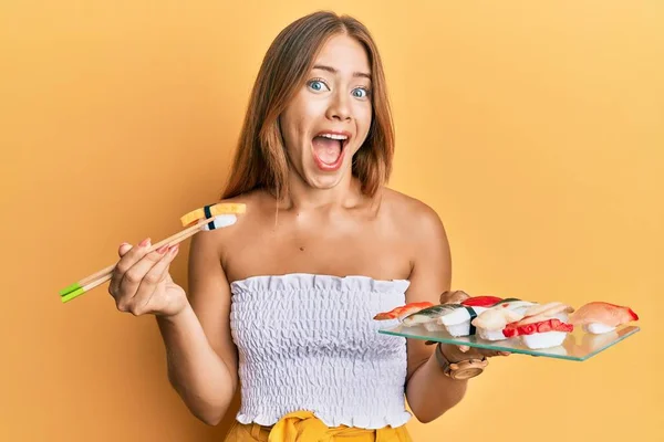 若いですブロンド女性食べるオムレツ寿司箸を使用してクレイジーを祝うと興奮叫んでオープン目で成功のために驚いて — ストック写真