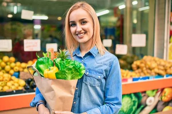 Joven Chica Rubia Sonriendo Feliz Sosteniendo Comestibles Bolsa Papel Pie —  Fotos de Stock