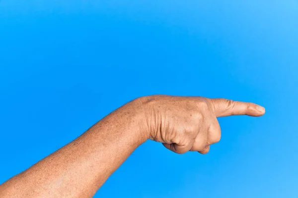 Рука Старшего Латиноамериканца Синем Изолированном Фоне Указывающая Указательным Пальцем Сторону — стоковое фото