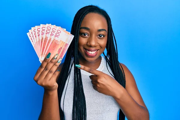 Joven Mujer Afroamericana Sosteniendo 100 Billetes Noruegos Sonriendo Feliz Señalando —  Fotos de Stock