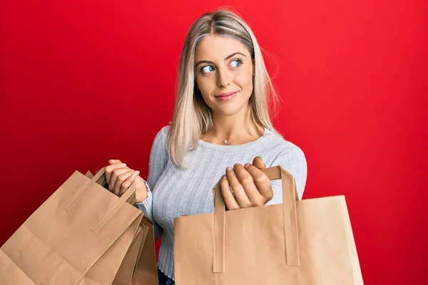 Vacker Blond Kvinna Håller Eco Kartong Shoppingväskor Ler Tittar Sidan — Stockfoto