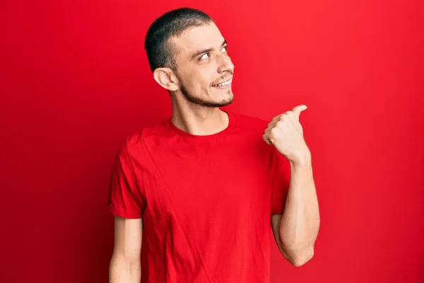 Jovem Hispânico Vestindo Casual Camiseta Vermelha Apontando Polegar Até Lado — Fotografia de Stock