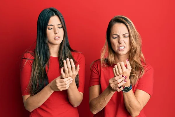 西班牙家庭的母亲和女儿穿着便衣 身穿红色背景的衣服 手指头疼痛 关节炎发炎 — 图库照片