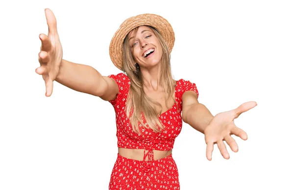 夏の帽子をかぶっている美しい白人女性は 抱擁のために開いた腕で笑顔カメラを見ています 幸せを受け入れる陽気な表情 — ストック写真