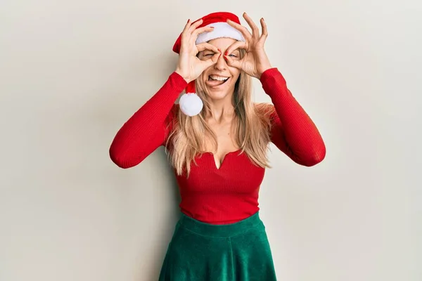 Beautiful Caucasian Woman Wearing Christmas Costume Hat Doing Gesture Binoculars — Stock Photo, Image