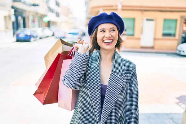 年轻美丽的女孩笑着对法国风格的手拿着购物袋在城市的街道上 — 图库照片
