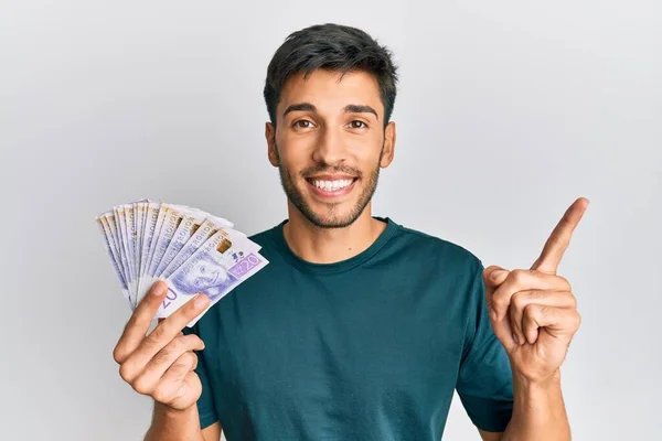 Joven Hombre Guapo Sosteniendo Billetes Coronas Suecas Sonriendo Feliz Señalando —  Fotos de Stock