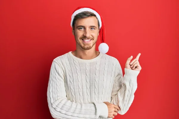Όμορφος Καυκάσιος Που Φοράει Χριστουγεννιάτικο Καπέλο Χαμογελώντας Χαρούμενος Δείχνοντας Χέρι — Φωτογραφία Αρχείου