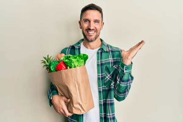 Hombre Guapo Con Barba Sosteniendo Bolsa Papel Con Comestibles Sonriendo —  Fotos de Stock