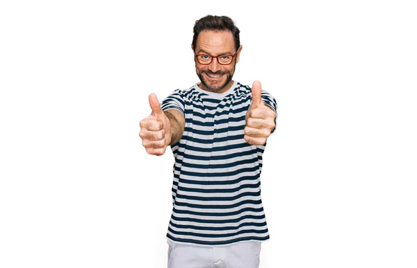 手で積極的なジェスチャーを行うことを承認カジュアル服や眼鏡を身に着けている中年の男性 親指アップ笑顔と成功のために幸せ 勝者のジェスチャー — ストック写真