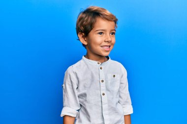 Sevimli Latin çocuk günlük giysiler giyiyor. Tarafsız görünmeye çalışıyor. Profil pozu veriyor, doğal bir yüz ve kendine güvenen bir gülümseme.. 