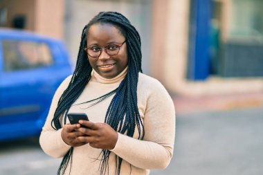 Genç Afrikalı Amerikalı kadın şehirde akıllı telefon kullanıyor..