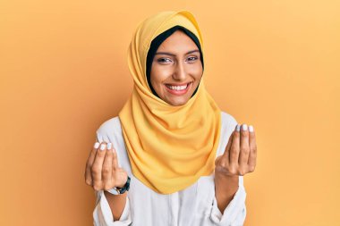 Genç esmer Arap kadın geleneksel İslami başörtüsü takıyor. Elleriyle para hareketi yapıyor. Maaş istiyor. 