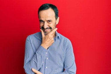 Orta yaşlı İspanyol bir adam gündelik kıyafetler giyiyor kameraya bakıyor kollarını kavuşturup gülümsüyor ve çenesini kaldırıyor. Olumlu düşünmek. 