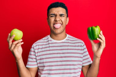 Genç Arap adam elinde yeşil elma ve biber tutuyordu. Dilini çıkarıyordu. Komik bir ifadeyle mutluydu.. 