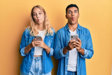 Akıllı telefon kullanan ırklar arası genç bir çift. Ağızlarıyla balık suratlı ve şaşı gözlü, çılgın ve komik.. 