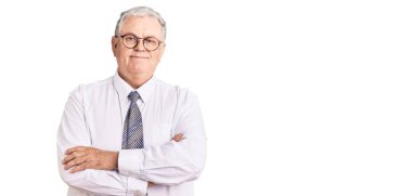 İş kıyafetleri giymiş, kollarını kavuşturup kameraya gülümseyen yaşlı, gri saçlı bir adam. pozitif kişi. 