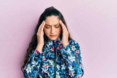 Güzel bir ortadoğulu kadın, stresten dolayı kafasında ağrı için elleri kafasında çiçek desenli bir ceket giyiyor. migren ağrısı. 