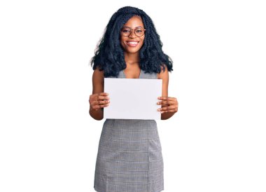 Güzel Afrikalı Amerikalı kadın boş pankart tutuyor. Olumlu ve mutlu görünüyor. Kendine güvenen bir gülümsemeyle dişlerini gösteriyor. 
