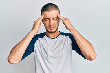 İspanyol genç adam stres yüzünden elleri başının üstünde gündelik giysiler giyiyor. migren ağrısı. 