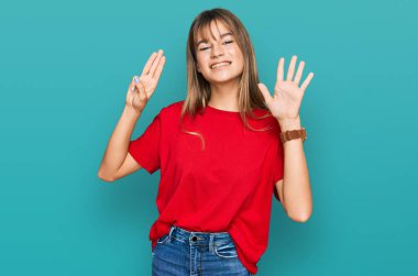 Gündelik kırmızı tişört giyen genç beyaz kız sekiz numarayı gösterip işaret ederken kendinden emin ve mutlu bir şekilde gülümsüyor.. 