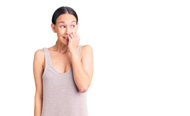 Güzel, esmer, sıradan bir elbise giyen, gergin ve elleri ağzında, tırnaklarını yiyen bir kadın. anksiyete. 