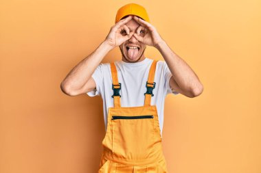 Ustabaşı üniforması giyen İspanyol genç adam dürbün gibi jest yapıyor, gözleri parmaklarından bakıyor. çılgın ifade. 