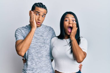 Gündelik giysiler giyen genç latin çift korkmuş ve şok olmuş, şaşırmış ve şaşırmış bir yüz ifadesi var. 