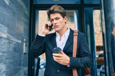 Kafkasyalı genç iş adamı ciddi bir ifadeyle akıllı telefondan konuşuyor ve şehirde kahve içiyor..