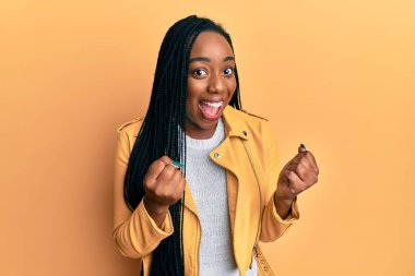 Sıradan bir ceket giyen genç Afrikalı Amerikalı kadın kollarını kaldırıp, gözlerini açarak başarının şaşkınlığını ve şaşkınlığını yaşıyor. Kazanan konsept. 