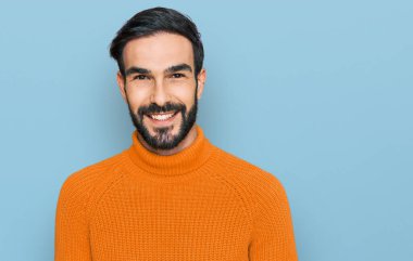 Yüzünde mutlu ve havalı bir gülümseme olan sıradan kıyafetler giyen genç İspanyol bir adam. şanslı kişi. 