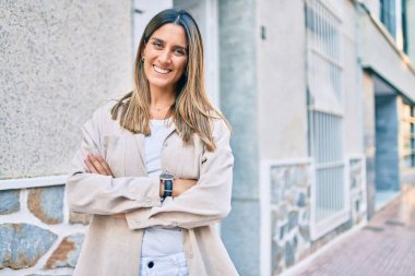 Genç beyaz kadın gülümseyerek şehirde mutlu mesut yürüyor..