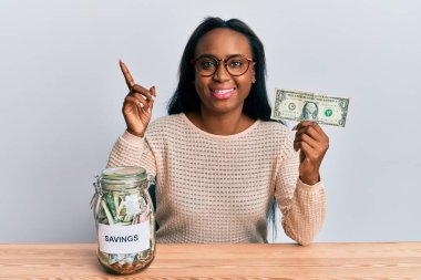 Elinde dolar ve kavanozla gülümseyen genç Afrikalı bir kadın. 