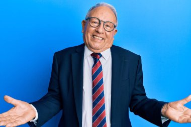 İş elbisesi giyen ve kravat takan kıdemli beyaz adam dostça bir karşılama, olumlu ve kendinden emin bir selamlama olarak gülümsüyor. 