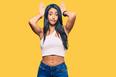 Güzel İspanyol kadın günlük kıyafetler giyip tavşan kulağı yapıyor. Avuçlarıyla alaycı ve şüpheci görünüyor. Paskalya tavşanı konsepti. 