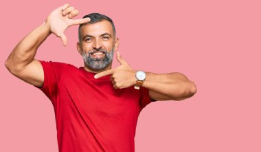 Orta yaşlı, sıradan kıyafetler giyen, gülümseyen, elleri ve parmakları gülen yüzlü bir adam. yaratıcılık ve fotoğrafçılık kavramı. 