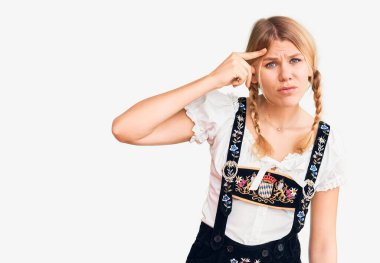 Oktoberfest elbisesi giyen genç sarışın kadın alnındaki sivilceden mutsuz olduğunu gösteriyor. Siyah noktalı çirkin bir enfeksiyon. sivilce ve deri problemi 