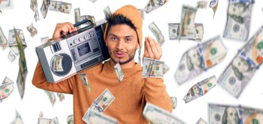 Yakışıklı Latin Amerikalı genç adam kasetçalar tutuyor, müzik dinliyor, italyan jestleri yapıyor, elleriyle ve parmaklarıyla kendinden emin ifade ediyor.