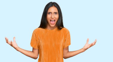 Genç esmer Arap kadın gündelik kıyafetler giyip deli gibi bağırıyor ve agresif bir ifade ve kollarla bağırıyor. hüsran kavramı. 